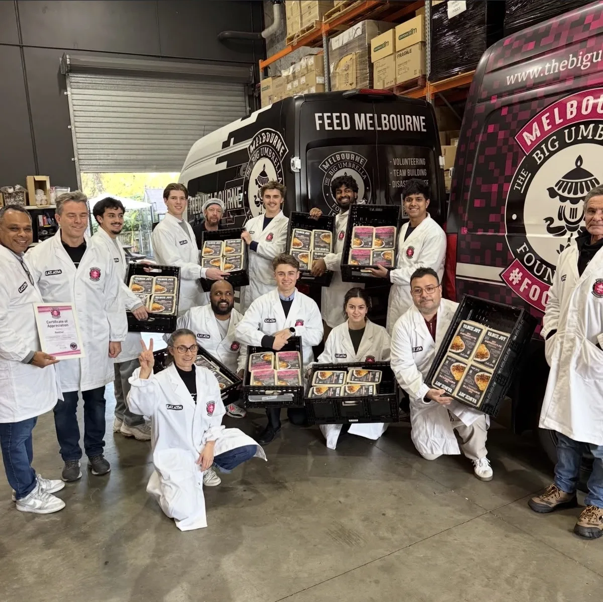 RedOwl team with The Big Umbrella Foundation volunteers holding crates of prepared meals